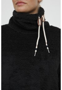Sort fleece pullover med høj krave. Har hvide snore med brune detaljer og en blød, struktureret overflade.