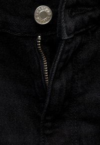 Tissu en denim noir présentant une fermeture éclair et un bouton en métal. La fermeture éclair est de couleur dorée avec des dents visibles et des détails de couture.