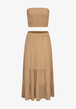 Beżowy zestaw składający się z dwóch części, zawierający top bez ramiączek z marszczonym wykończeniem oraz długą spódnicę w warstwy z elastycznym paskiem, wykonany z lekkiego materiału.