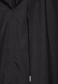 Black fabric with a smooth texture, featuring a v-shaped neckline, vertical stitching lines, and a cord with a metal toggle at the hem.