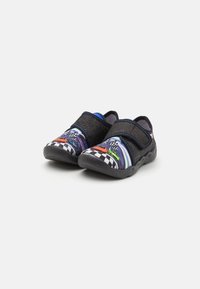 Čierne slip-on topánky s farebnými grafikami pretekárskych áut, šachovnicovým vzorom a suchým zipsom; gumová podošva s textúrovaným povrchom.