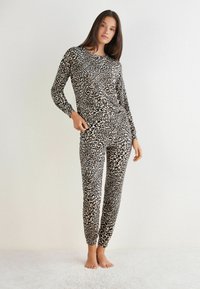 Leopardenmuster-Loungewear-Set aus weichem Material, bestehend aus einem langärmligen Oberteil und enganliegenden Hosen mit elastischen Bündchen, in Schwarz- und Beigetönen.