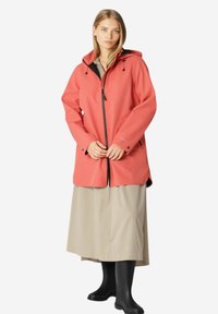 Chaqueta coral, impermeable, con capucha, cremallera frontal y cordones ajustables. Presenta un corte relajado y mangas largas.