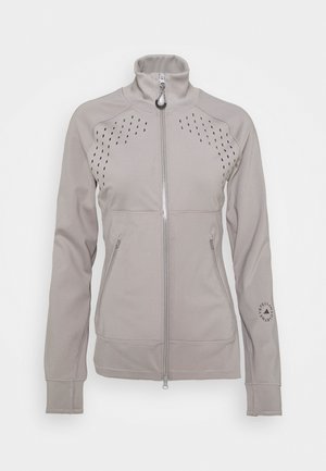 Jasnoszara kurtka zapinana na zamek z wysokim kołnierzem, perforowaną wentylacją na piersi, dwoma kieszeniami na zamek z przodu oraz logo na mankiecie lewego rękawa.