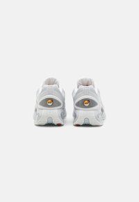 Witte sportschoenen met grijze accenten, bovenkant van mesh, gevoerde kraag en kenmerkende luchtkussens. Looppatroon zichtbaar op de buitenzool.