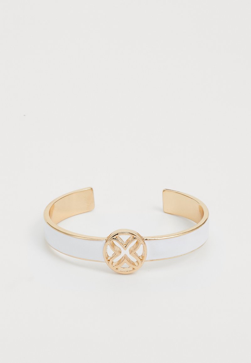 Bracciale a manica in metallo dorato con una fascia bianca lucida e un accento circolare decorativo al centro che presenta un design intricati.