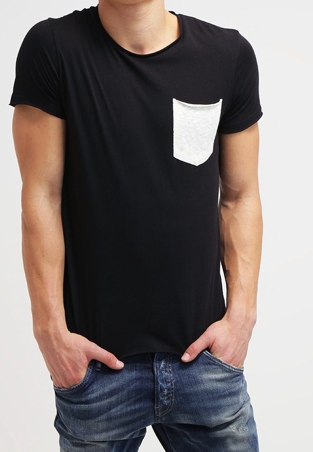 Sort t-shirt med korte ærmer og en hvid, tekstureret lomme. Stoffet ser blødt og strækbart ud, sammen med blå denim jeans.