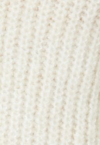 Cremefarbener Strickstoff mit einer weichen, strukturierten Oberfläche. Verfügt über ein dezentes Muster aus erhabenen Stichen, das Tiefe und Dimension verleiht.