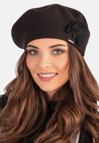 Sort strikket basker med en dekorativ sort blomstervægt med perler, en glat overflade og en klassisk rund form.