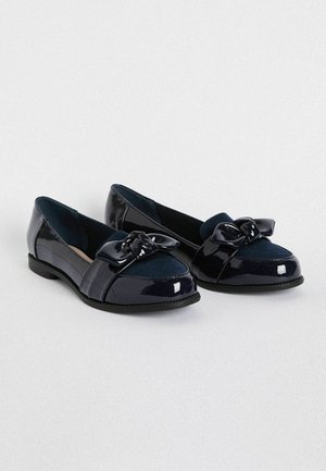 Mocasines de charol azul marino con un lazo de ante sintético y puntera redonda. Presentan un tacón bajo y una suela texturizada para mayor agarre.