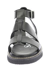 Sandale en cuir noir avec des lanières entrecroisées, fermeture à boucle à la cheville, semelle texturée et légère surélévation avec un bord cousu.