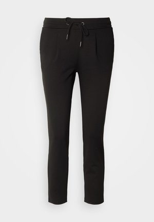 Pantalons de jogging noirs en matériau doux, avec une taille élastique à cordon de serrage, deux poches avant, des jambes fuselées et de légères plis avant.