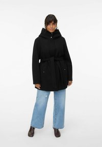 Manteau noir ceinturé avec un col haut et une capuche ; fabriqué dans un tissu doux. Il dispose de poches latérales, de manches longues et d'une silhouette épurée.