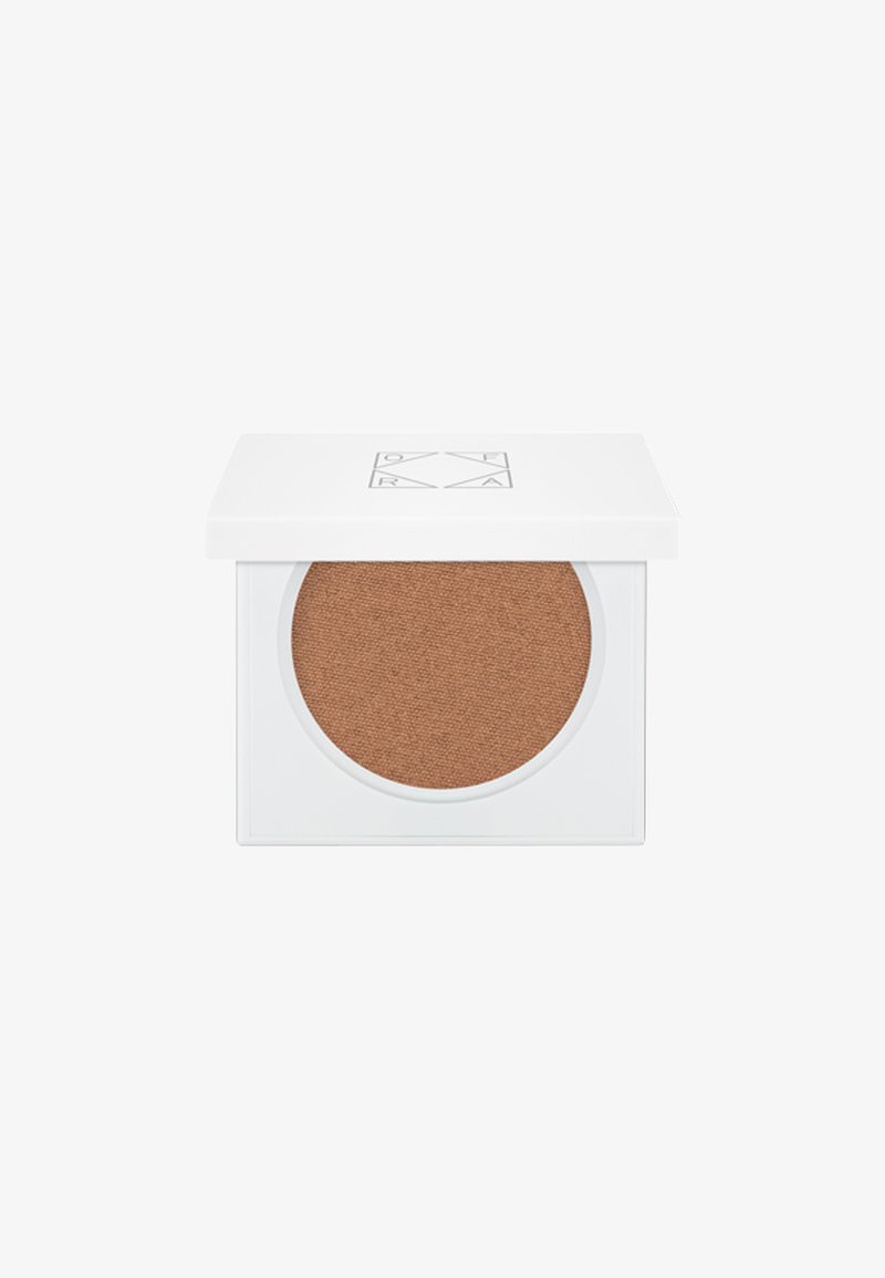 Poudre brune dans une poêle ronde à l'intérieur d'un compact blanc carré. Le couvercle présente un logo minimaliste et s'ouvre pour révéler une surface texturée.