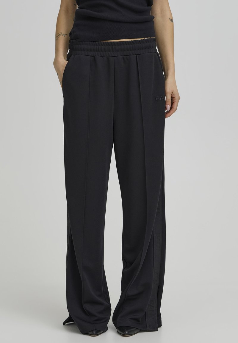 Pantalones negros de pierna ancha con cintura fruncida, con aberturas laterales y una sutil marca. Confeccionados en una tela suave y texturizada para mayor comodidad.