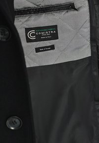 Czarna pikowana tkanina z gładkim wnętrzem. Oznaczona metką z napisem "COMISTRA", "Tkaniny Ekologiczne" oraz informacjami "Wyprodukowano we Włoszech".