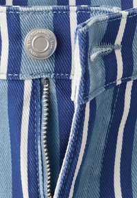 Tissu rayé bleu et blanc montrant une fermeture éclair partiellement ouverte et un bouton métallique avec une boutonnière cousue.