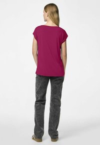 Fuksjowa koszulka z krótkimi rękawami, w zestawie z teksturowanymi szarymi spodniami. Tył prezentuje prosty wzór oraz luźny krój, odpowiedni na codzienne noszenie.