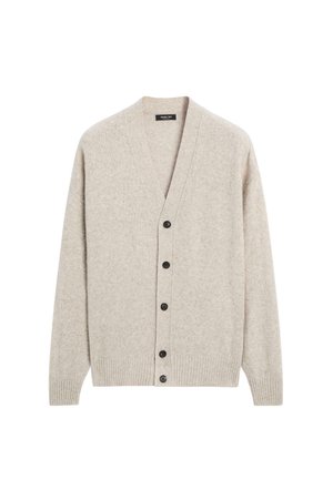 Beige vest gemaakt van zachte stof, met een diepe V-hals, lange mouwen en zes zwarte knopen aan de voorkant. Gestructureerd breipatroon.