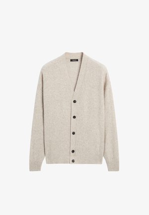 Beige vest gemaakt van zachte stof, met een diepe V-hals, lange mouwen en zes zwarte knopen aan de voorkant. Gestructureerd breipatroon.