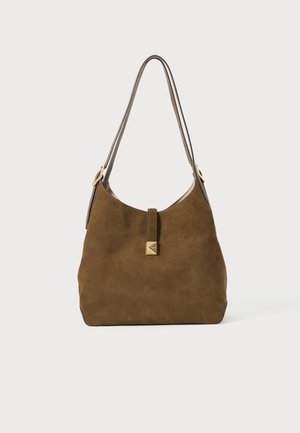 Brown suede bag with a rounded shape, thin shoulder strap, gold-tone hardware, and a front tab detail. Soft texture with minimal accents.