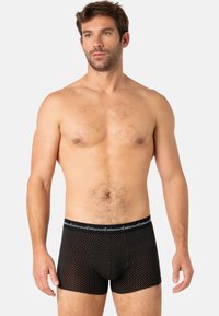 Caleçons-boxers noirs avec un motif à pois, taille élastique portant l'étiquette "Eminence", tissu doux et forme ajustée.