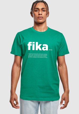 T-shirt verde din bumbac, cu mâneci scurte, care prezintă cuvântul "fika" într-un font alb mare. Include o descriere mai mică dedesubt.