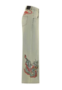 Lichtgroene wijde jeans met een zijborduursel van een draak in rood en blauw, met een zwart label op de tailleband en achterzak.