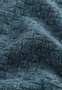 Tejido texturizado en azul y gris con un patrón a cuadros, que presenta una superficie suave y borrosa, y tonos de color ricos y variados.