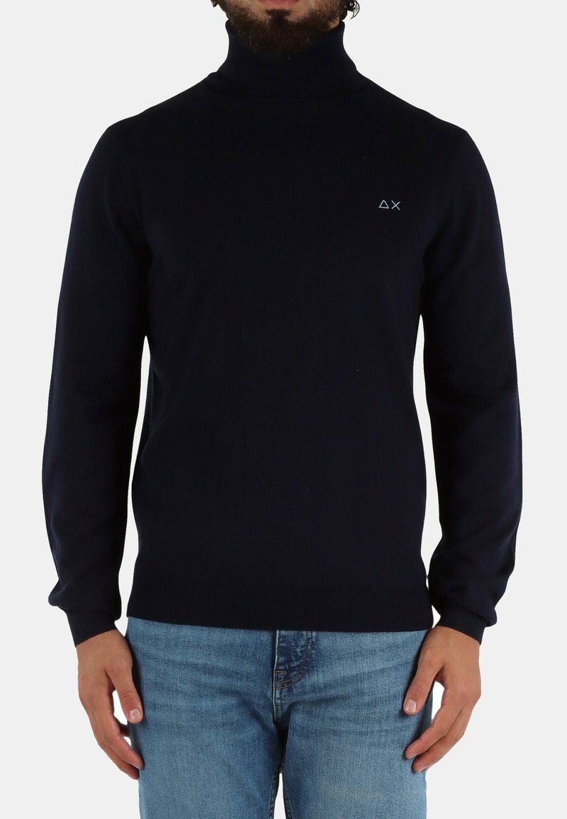 Maglione a collo alto blu navy realizzato in morbido tessuto a maglia. Caratterizzato da una vestibilità aderente con polsini a coste e un piccolo logo sul petto.