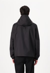 Sort vandtæt jakke med hætte, elastiske manchetter og solidt design. Har minimal detaljering og en afslappet pasform.