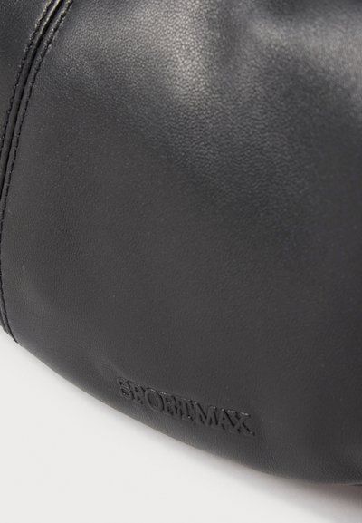 Gros plan sur un cuir noir texturé avec des coutures piquées et le nom de la marque SPORTMAX embossé.
