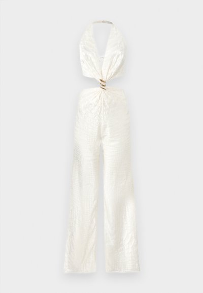 Άσπρη ολόσωμη φόρμα με λαιμόκοψη halter, με υφή στο ύφασμα, φαρδιές παντελόνες και κόμπο στριφογυριστό στη μέση.