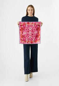 Écharpe en soie florale de couleur rose vif avec des fleurs rouges et blanches, bordée de vert foncé. Forme carrée, texture lisse, motif détaillé.