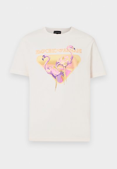 Jasny beżowy t-shirt z graficznym wzorem przedstawiającym dwie różowe flamingi w żółtej trójkątnej ramce, z napisem "EMPORIO ARMANI" powyżej.