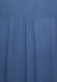 Tessuto blu con sottili pieghe verticali e una superficie liscia, leggermente texture.