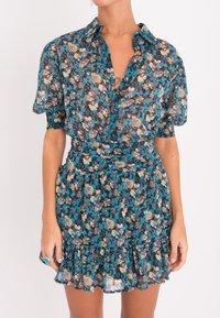 Kukkamekko, jossa on teal-väri ja vaaleanpunaisia sekä beigen värisiä kukkia, lyhyet puff-hihat, kauluksellinen pääntie, vyötärönauha ja röyhelöhelma.