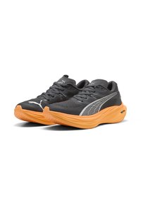 Scarpe sportive grigie con tomaia in mesh, intersuola in schiuma arancione e suola testurizzata. Presentano il logo PUMA e dettagli riflettenti.