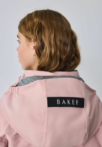 Rozā ūdensnecaurlaidīga jaka ar kapuci, uz kuras aizmugurē ir melna zīmola etiķete "BAKER", un pelēka strukturēta akcenta detaļa gar pleciem.