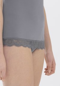 Débardeur gris avec des bordures en dentelle, à la finition lisse, présentant un ourlet festonné et un délicat motif floral en dentelle en bas.
