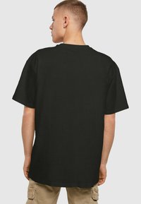 Sort kortærmet t-shirt med rund halsudskæring og en afslappet pasform, vist fra ryggen. Ingen synlige mønstre eller logoer.