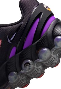 Musta urheilukenkä, jossa on teksturoidulla verkkopäällisellä, violetit korostusyksityiskohdat ja näkyvä ilmavaihtojärjestelmä pyöreässä, läpikuultavassa designissa.
