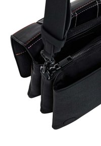 Borsa a tracolla nera in tessuto con tre scomparti, cuciture in contrasto, tracolla regolabile e tasca con zip per una conservazione sicura.