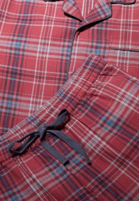 Punainen ja sininen ruudullinen yöasu, jossa on napitettava paita kauluksella ja yhteensopivat kiristysnarut.