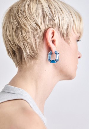 Blaue geometrische Acryl-Ohrringe mit einem geschichteten hexagonalen Design, das eine Mischung aus transparenten und festen Abschnitten aufweist.