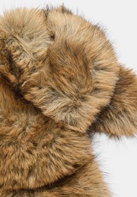 Zbliżenie na miękką, brązowo-czarną tkaninę z futra syntetycznego o gęstej, puszystej fakturze na białym tle.