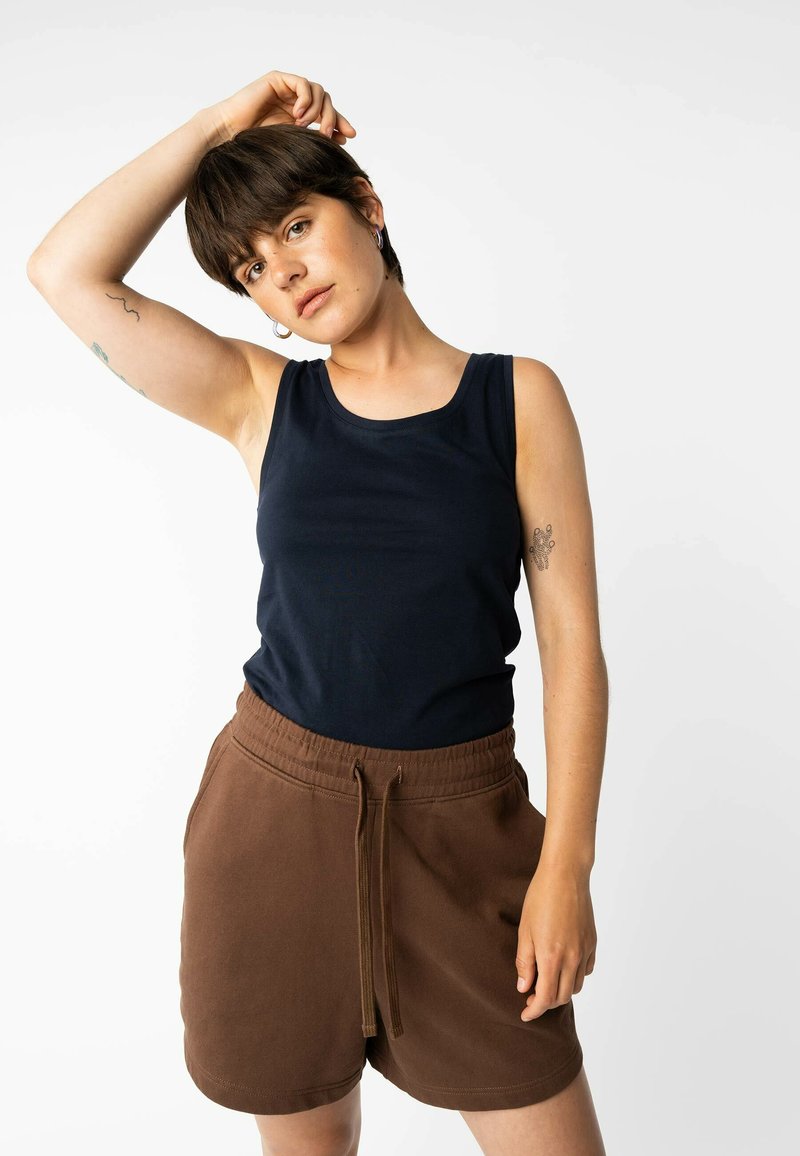 Marineblauses aus Baumwolle, kombiniert mit braunen Shorts. Die Shorts verfügen über einen elastischen Bund mit Kordelzug und haben eine glatte Textur.