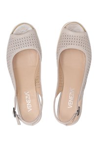 Beige Sandalen mit offenem Zehenbereich, einem perforierten Lederobermaterial, gepolsterter Innensohle und einem Cut-out-Design. Mit einem Slingback-Riemen und silberfarbenen Beschlägen.
