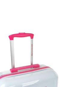 Maleta dura con superficie blanca brillante, cremallera rosa y asa a juego; asa retráctil metálica plateada; logo de la marca visible.