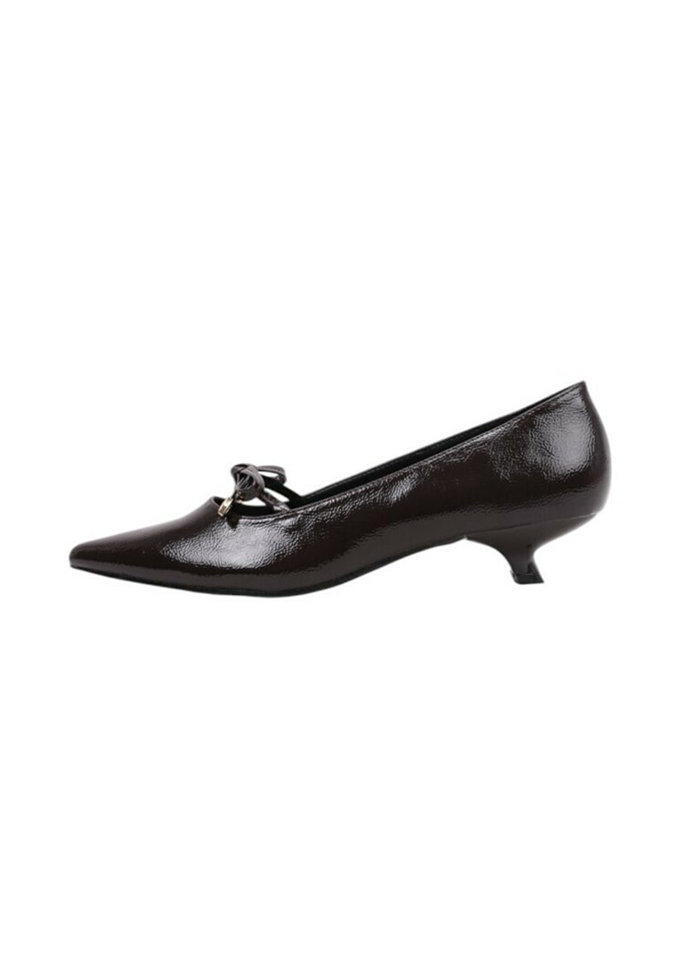 Zapatos de charol negro con punta afilada, un tacón bajo estilo kitten y un detalle de lazo decorativo en la parte delantera. Textura suave y brillante.